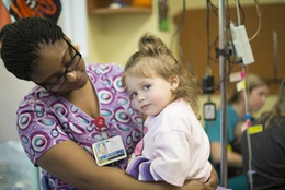 Nurse hugging a child in an exam room