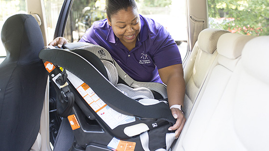 Lauren Brown, certified car seat tech, installs car seat for patient family