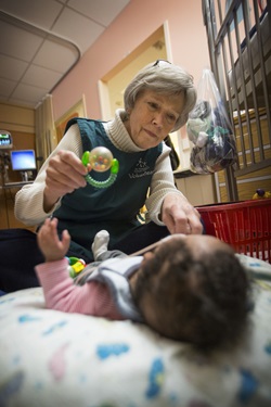 Volunteer holding a baby rattle while interacting with a baby