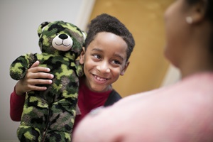 Boy holding a stuffed animal and smiling during a sleep study