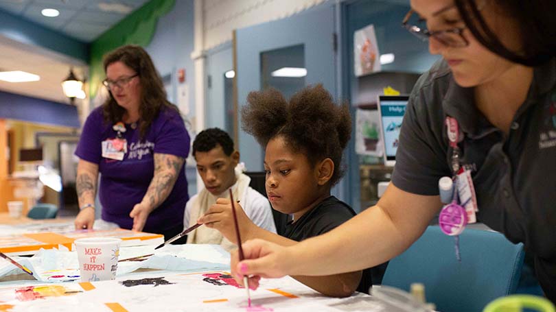 A MWPH patients and staff members make ceiling tile artwork as part of an evening activity.